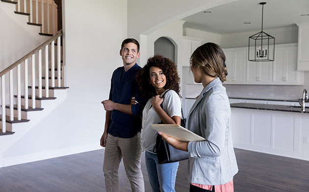 A couple and their realtor standing in an empty house. 