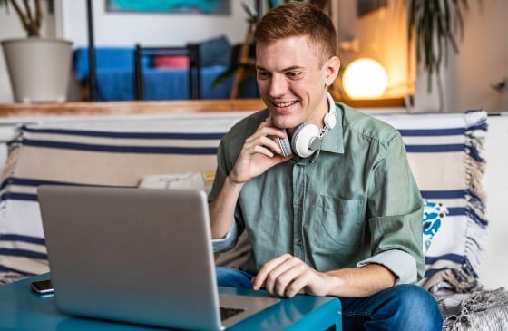 Young man smiling and using his laptop.