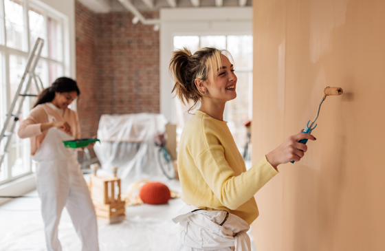 Woman using a roller to paint the wall in a living room