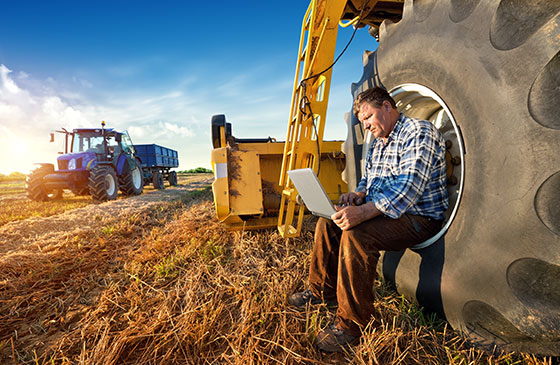 Farmer sitting on a tracker working on a computer