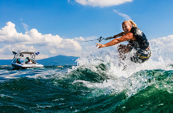 Woman gives a thumbs-up as she water skies attached to the back of a boat!