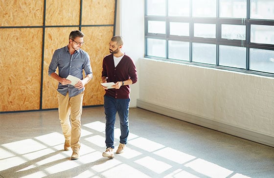 Two people walking in an empty business room. 