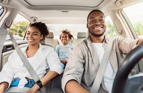 Familia sonriendo dentro de un automóvil.