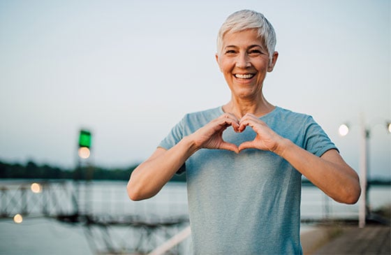 Woman makes heart shape with her hands.