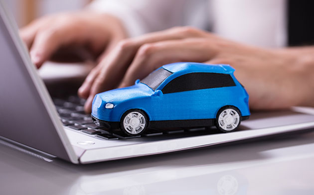 A blue toy car sitting on top of a laptop keyboard.