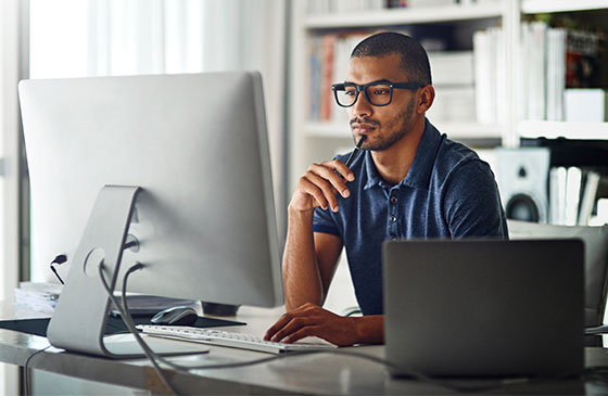 Young man with glasses looking at computer monitor