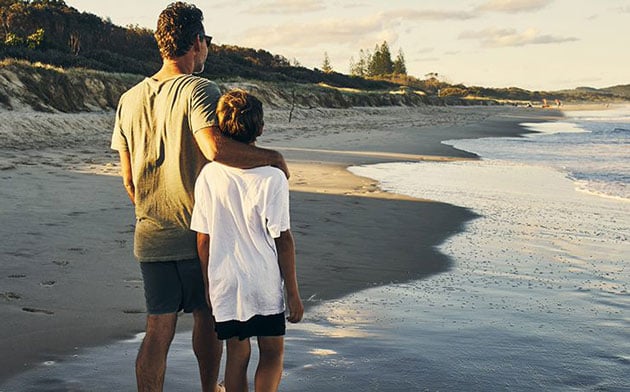 Father And Son Standing On The Beach 