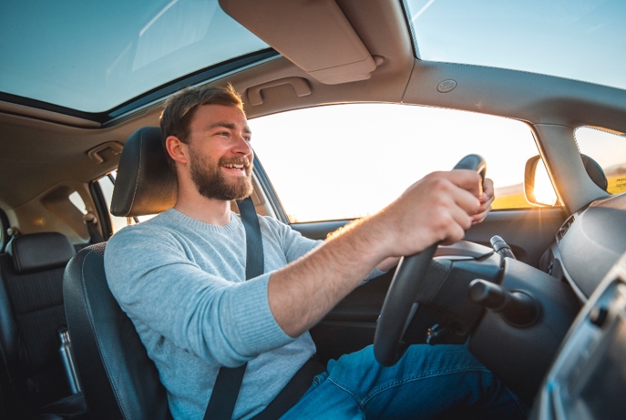 Hombre sonriente conduciendo dentro de su coche.