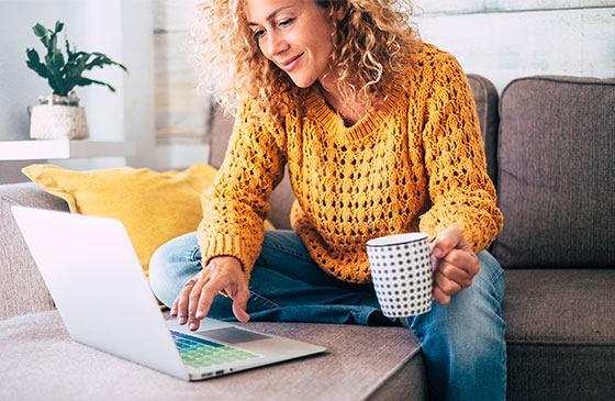 Lady in orange working on computer with coffee