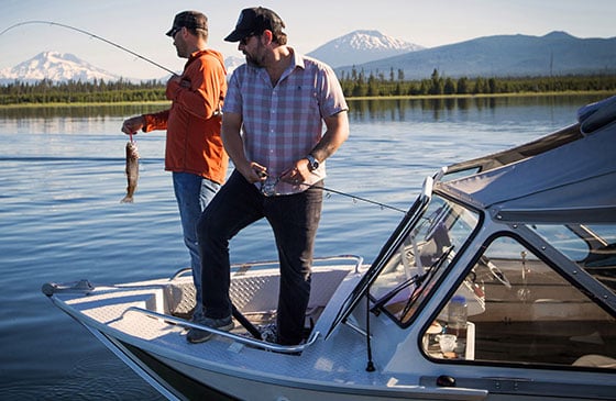 Two men fishing from the bow of their boat.