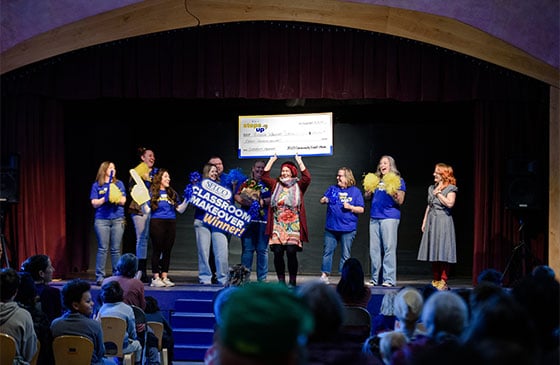 Classroom makeover recipient holding a check. 
