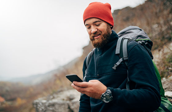Bearded man with backpack, knit cap and phone 