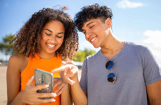 Guy and girl smiling while looking at a phone. 