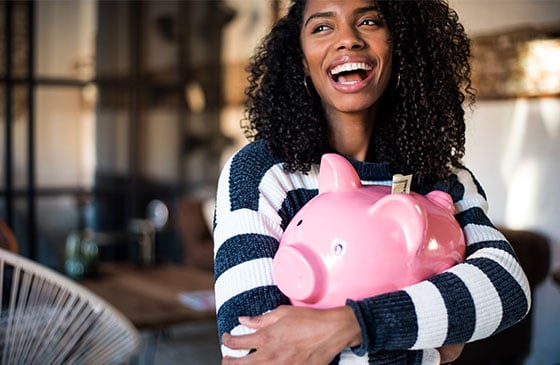 Young girl holding a pink piggy bank with money