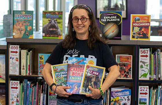 Martha Dyer standing inside classroom holding books