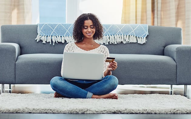 Woman sitting on floor with credit card and laptop