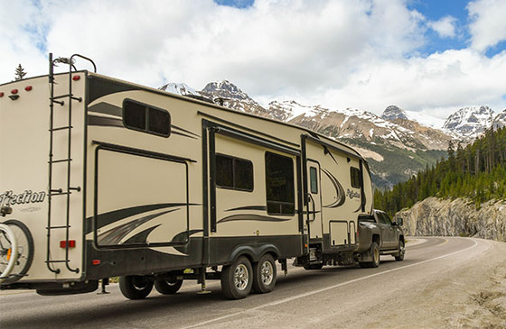 RV parked along the interstate surrounded by tall mountain ranges.