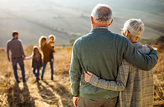 Older adults standing with family outdoors, illustrating wealth transfer planning, estate planning, and the transition of assets to heirs across generations.