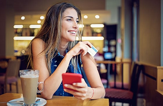 Young lady sitting in coffee house using phone