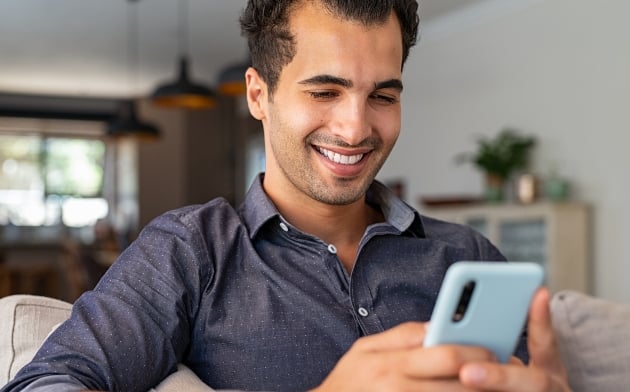 Young man on his phone smiling at the screen.