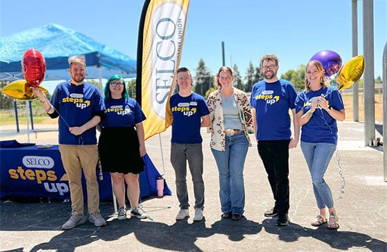 SELCO employees in Steps Up t-shirts standing outside. 