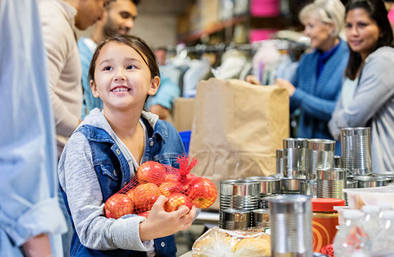 Young girl holding apples.