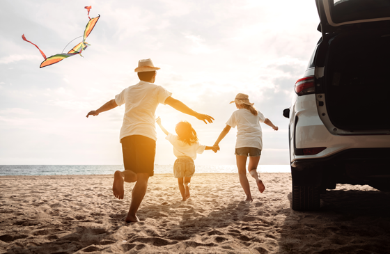 Family at the beach flying a kite near their SUV