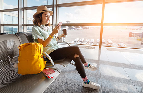 Women sitting at the airport using phone to set a bank travel notice