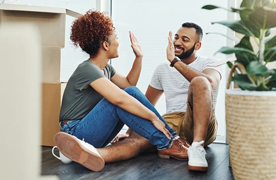 First-time homebuyers sitting among moving boxes in a new home, celebrating the start of their homeownership journey with guidance and resources from SELCO.