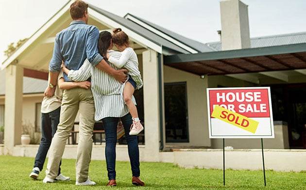 Young family looking at their home after it sold.