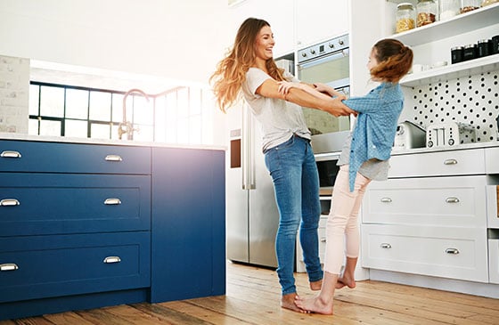 Mother and daughter spinning in circles in the kitchen