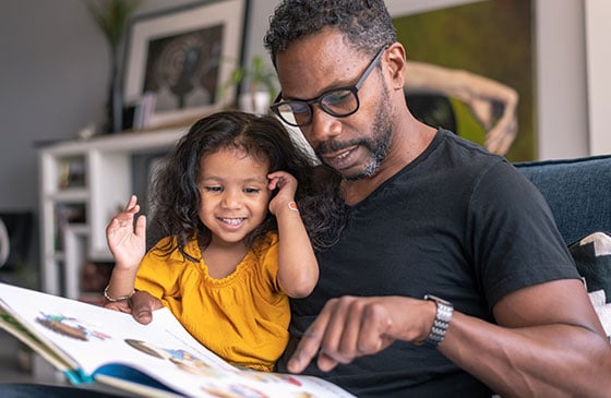 Father and daughter reading together on the sofa