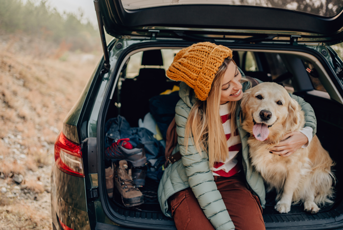 Girl sitting with golden retriever in the back of new Subaru Outback