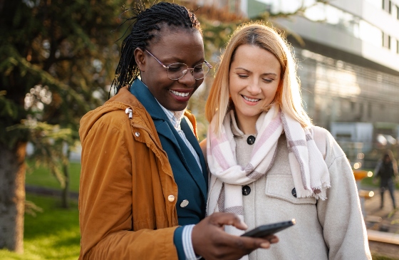 Two women smiling and looking at a phone.