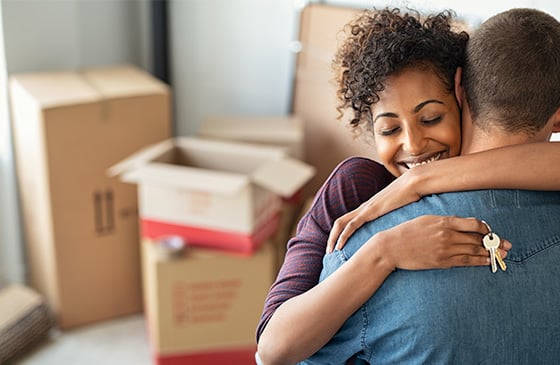 Couple hugging with keys to new home in hand