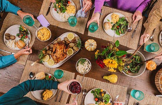 Friends and family sharing a meal around a dinner table, representing easy money transfers with Zelle® through the SELCO app for splitting bills, paying rent, sending gifts, and person-to-person payments.