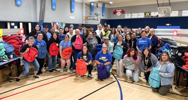Group of people holding backpacks and smiling