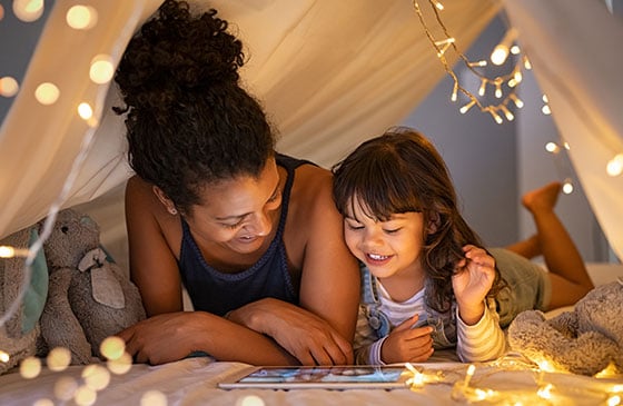 Daughter and mother reading together under tent