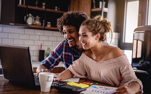 Couple look at laptop together.