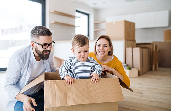 Toddler in a box, with his parents looking on.