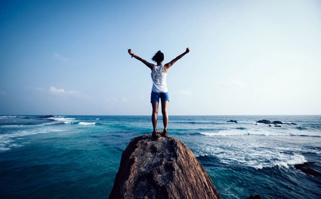 Person standing at the ocean with arms out