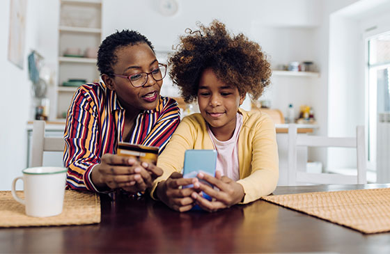 Mother teaching daughter about money management on phone