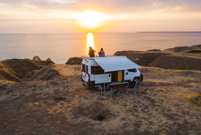 Two people watching the sun set from top of new Sprinter van
