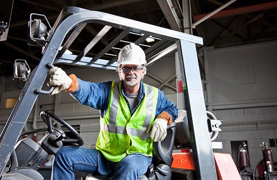 Construction worker standing on a forklift 